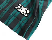 Load image into Gallery viewer, This is a photo of the SleeperBear black and white logo on the green and black stripped Hamfast athleisure shorts

